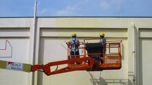 Vortex staff spray painting a building exterior