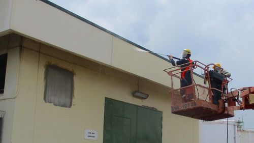 Vortex staff spray painting the top of a building