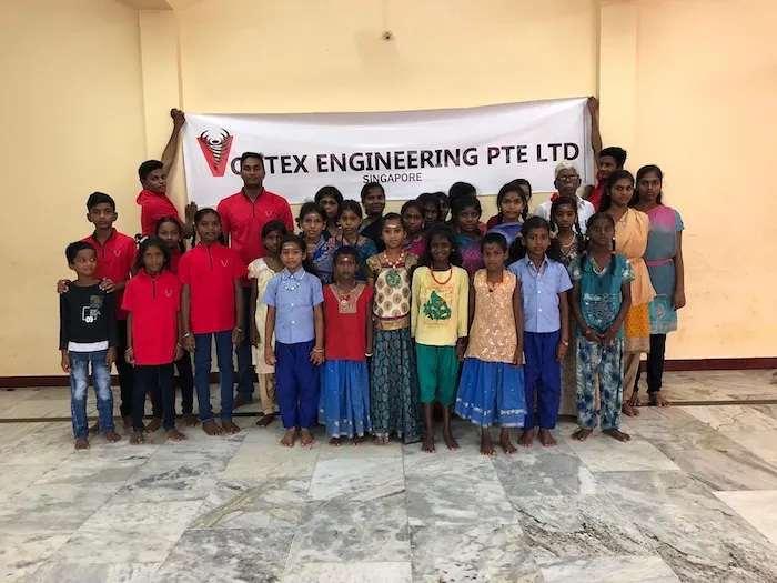 Vortex staff in a group photo with children during an outreach in India